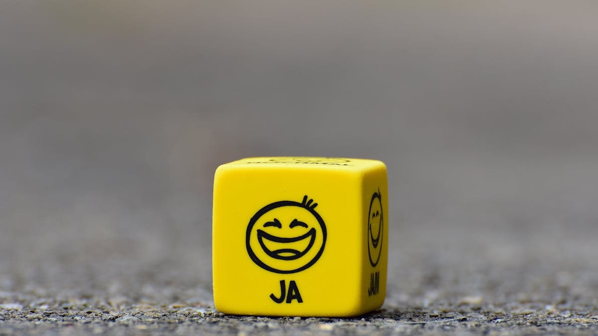 Close-up of a yellow dice featuring a smiley face emoticon symbolizing happiness and fun.